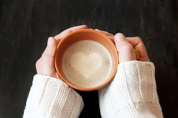 Mãos segurando xícara de café com forma de coração — Fotografia de Stock