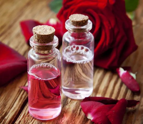 Rosenessenz-Flaschen mit Blütenblättern — Stockfoto