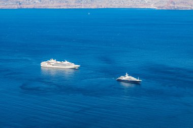Yunanistan 'ın derin mavi deniziyle Ege adasında demirli ahşap güverteli lüks egzotik yatın havadan çekilmiş resmi..