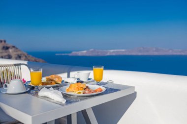 Breakfast time in Santorini in hotel. Luxury mood with fresh omelet and fruits with juice over sea view. Luxurious summer traveling holiday background. Happy relax vibes, couple morning closeup table clipart