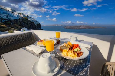 Oteldeki Santorini 'de kahvaltı zamanı. Taze omletle lüks bir ruh hali ve deniz manzaralı meyve suyu. Şatafatlı yaz tatili geçmişi. Mutlu rahatlama titreşimleri, çift sabah yakın çekim masası