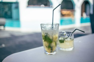 Tatil köyünün kenarında mojito kokteyli. Lüks tatil kavramı. Açık havuz arka planı, rahat eski moda renkli yakın çekim. Bulanık otel havuzuyla rahatla