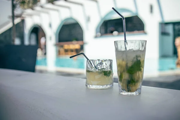 Mojito cocktails at the edge of a resort pool. Concept of luxury vacation. Outdoor bar pool background, relax vintage colored closeup. Relax pool with blurred hotel