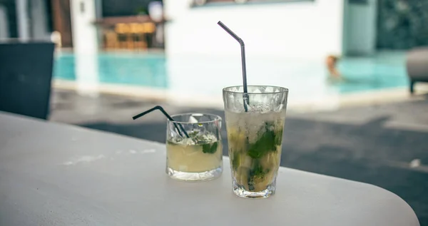 Mojito cocktails at the edge of a resort pool. Concept of luxury vacation. Outdoor bar pool background, relax vintage colored closeup. Relax pool with blurred hotel