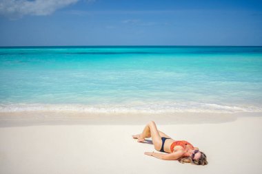 Bikinili güzel bir kadın sahilde dinleniyor.