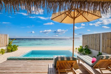 Açık hava turizmi. Yüzme havuzu, plaj sandalyeleri ya da şemsiyelerin altında palmiye ağaçları ve mavi gökyüzü olan lüks plaj tatil köyü. Egzotik yaz seyahati ve tatil geçmişi