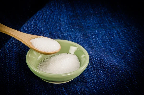 Zucker auf Holzlöffel auf blauem Stoff — Stockfoto