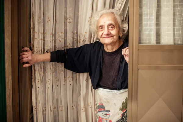 Mulher velha olhando para fora da porta — Fotografia de Stock