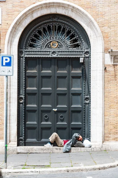 イタリアのローマの古いドアに寝たきりのホームレスの男が横たわっていた — ストック写真