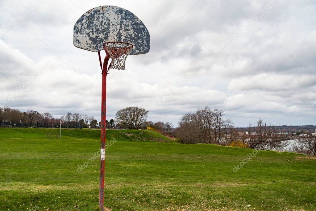 Old outdoor baskeball hoop with the broken wooden backboard in a park in Portland Maine, USA