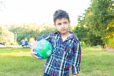 Düşünceli bir çocuğun elinde bir dünya var. Dışarıdaki bir çocuğun portresi.