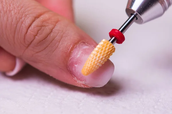 removing the gel polish coating from the nails with a ceramic cutter.