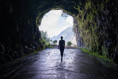 Tanınamayan bir kadının silueti Madeira adasının dağlarındaki eski Sao Vicente yolunda dramatik bir tünelden dışarı bakıyor..