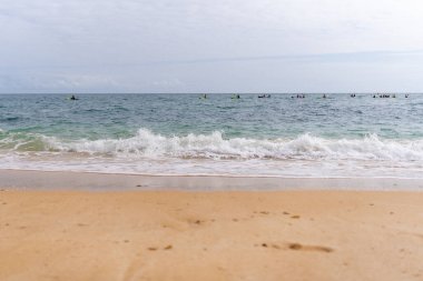 View to waves from coast, in horizont seeing kayakers. Algarve region, Portugal.