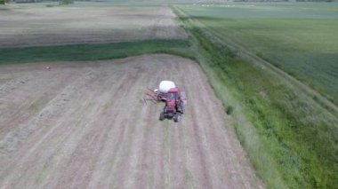 Plunge İlçesi, Litvanya - 24 Haziran 2022: Traktörün beyaz filmle nasıl balya yaptığını gösteren hava manzarası