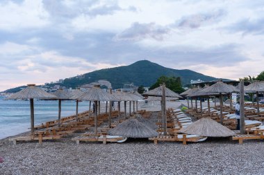 Budva, Karadağ - 8 Temmuz 2022: Akşam saatlerinde boş plaj sandalyeleri.