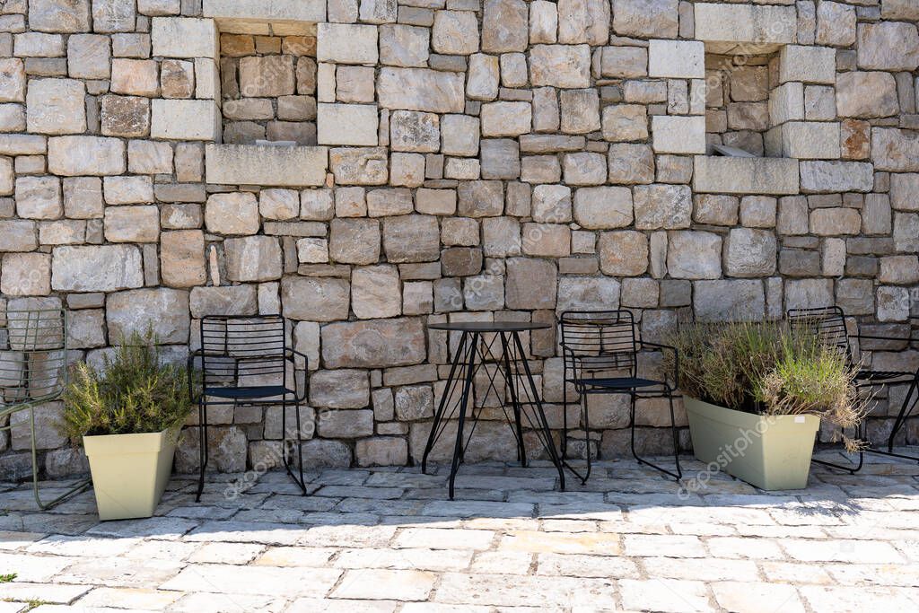 Chairs and table by the wall under pergola.