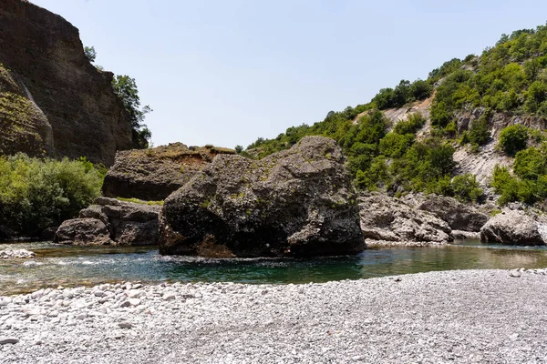 Low angle of view from river. We can see water and rock in river.