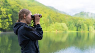 Karadağ 'ın Biogradska Gora kentindeki Biogradsko gölünde dürbünlü bir kadın.
