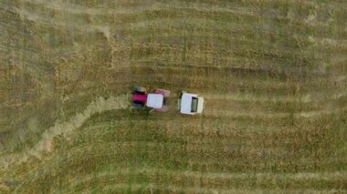 Plunge. Lithuania - 17 August 2022: Baler wrapper working on the  field. View from top.