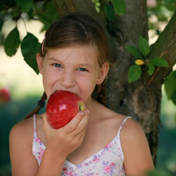 Liten flicka bita i ett äpple — Stockfoto