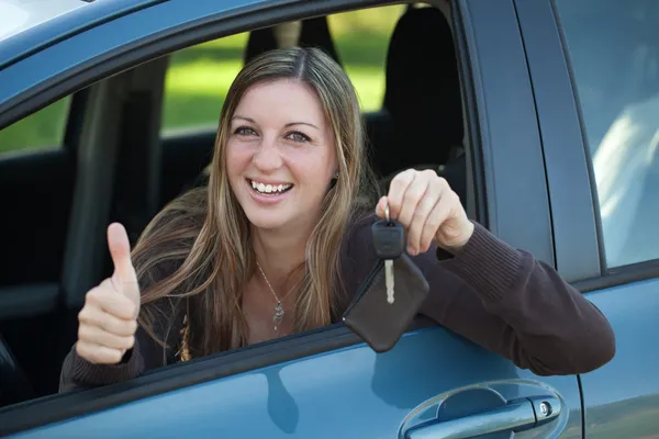 車のキーを示す女性の笑みを浮かべてください。 — ストック写真