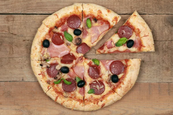Pizza Deluxe en rodajas sobre una mesa de madera —  Fotos de Stock