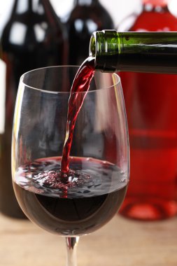 kırmızı şarap bardağa dökülüyor.