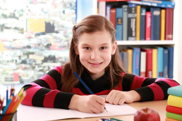 Chica sonriendo mientras haciendo la tarea — Foto de Stock