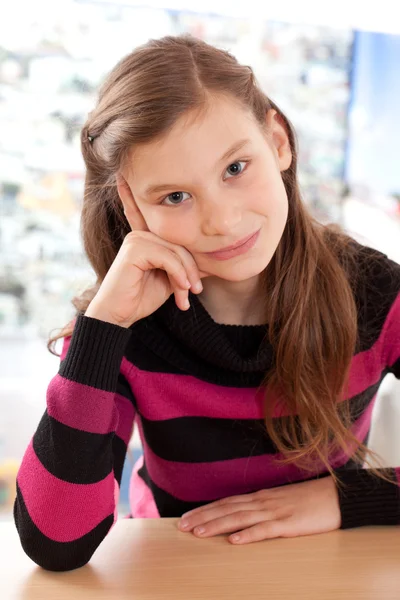 Flickan tänker medan du sitter vid ett skrivbord — Stockfoto