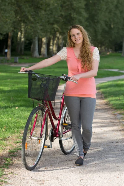 Ung kvinna står bredvid hennes cykel — Stockfoto