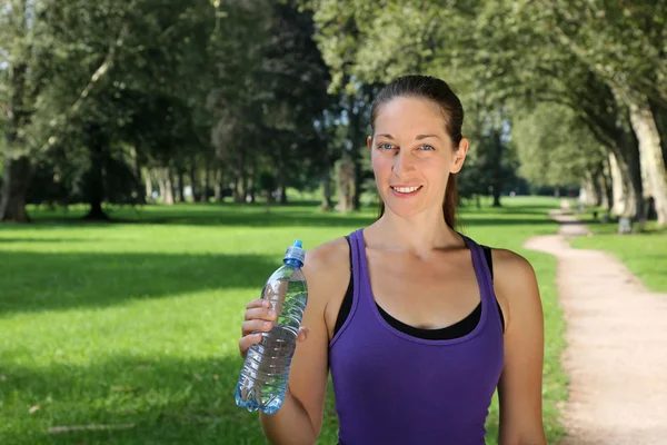 Athletic young woman with a water bottle — Stockfoto