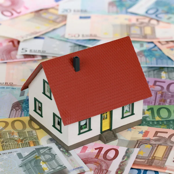 Bank financing a real estate with a house on banknotes — Stock Photo, Image