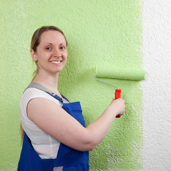Mujer sonriente pintando con rodillo de pintura —  Fotos de Stock