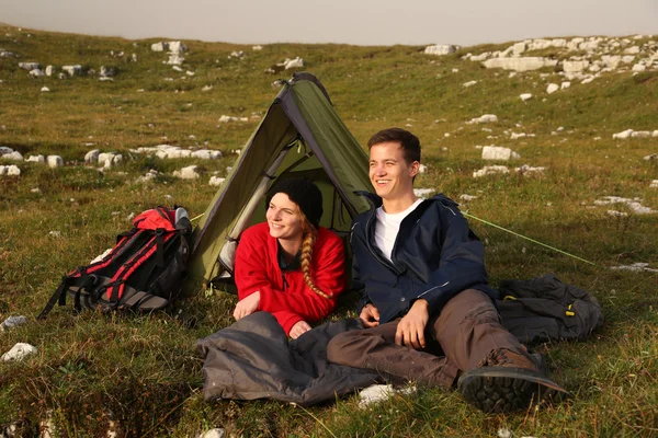 Young couple watching the sunset while camping in the mountains — Stock Photo, Image