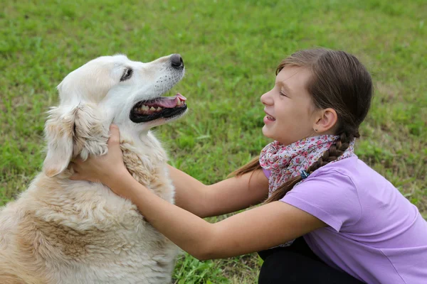 Enfant embrassant chien sur une prairie — Photo