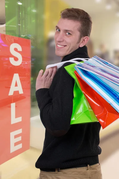 Hombre sonriente con bolsas de compras en una tienda de ropa —  Fotos de Stock