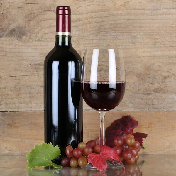 Rotwein in Weinflasche vor einem hölzernen Hintergrund — Stockfoto