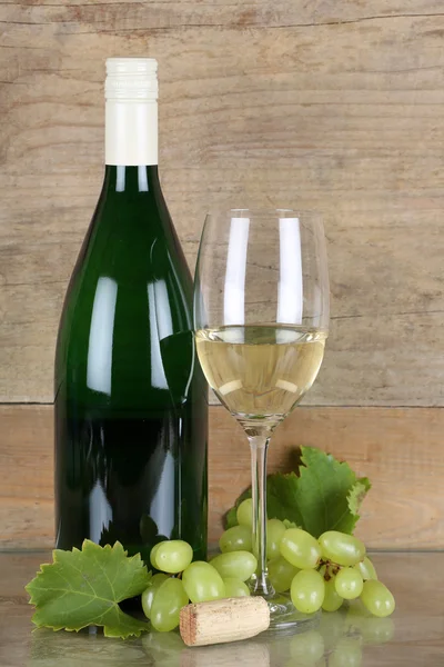 Vin blanc en bouteille et verre devant un fond en bois — Photo