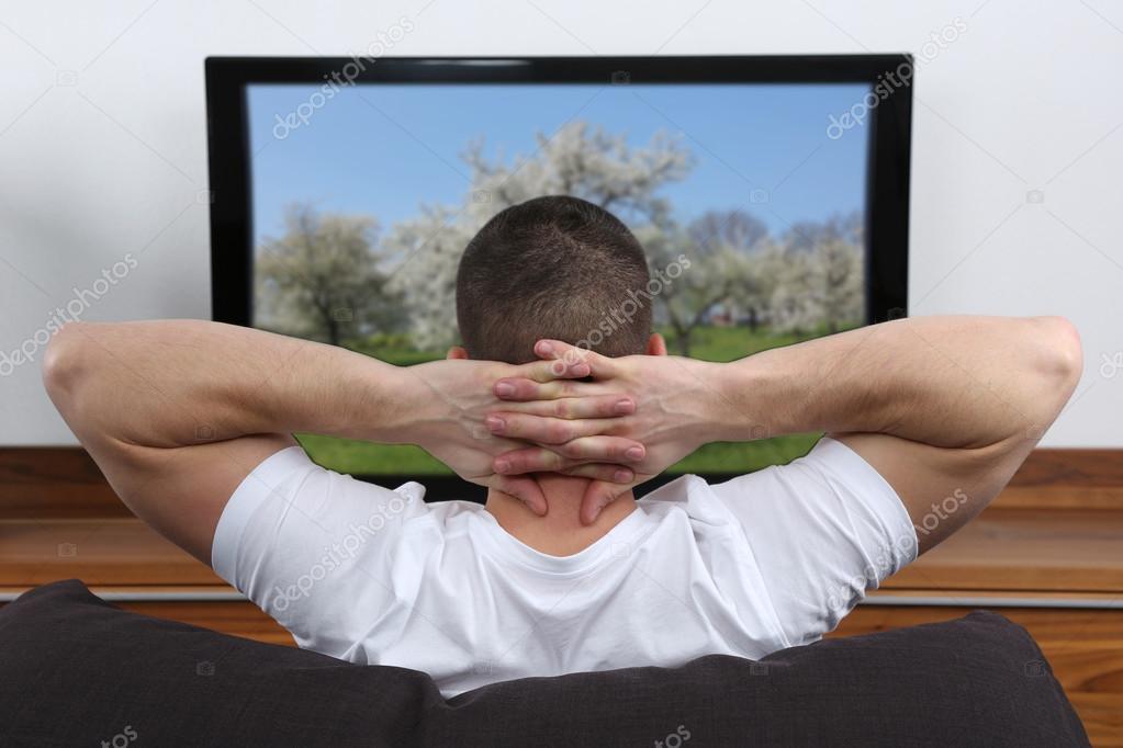 Jeune homme regardant la télévision image libre de droit par Boarding2Now © 41606479
