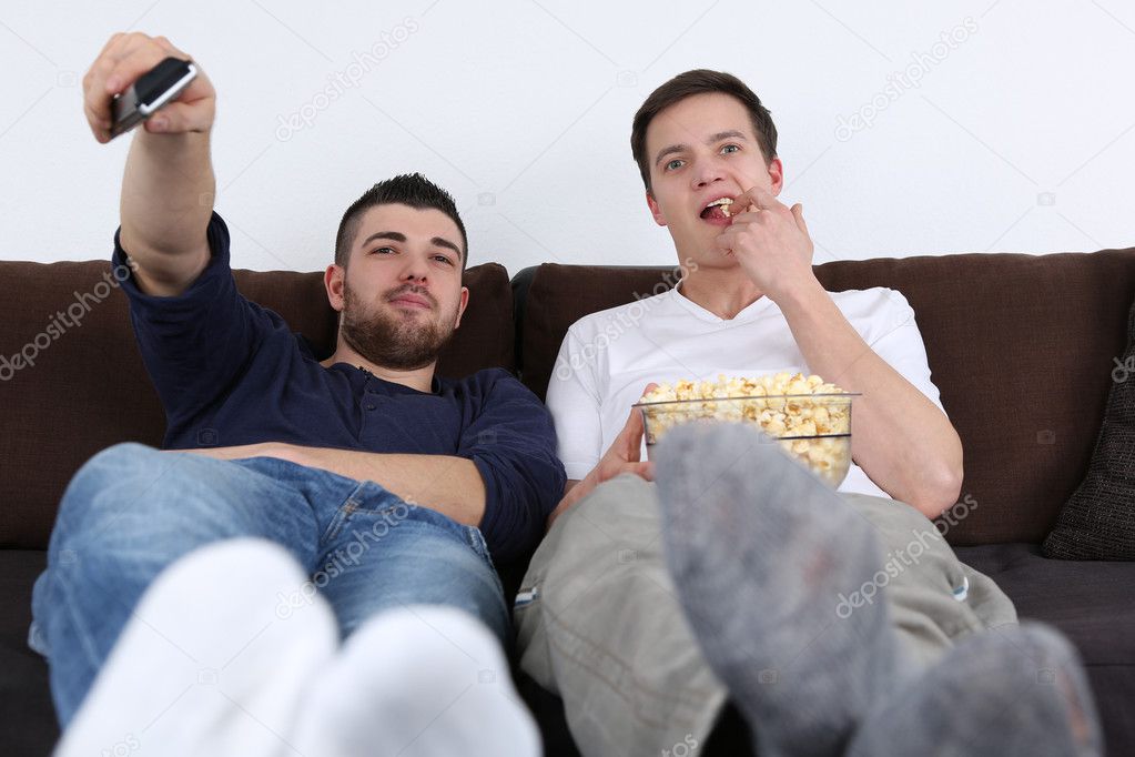 Young people relaxing and eating popcorn while watching tv