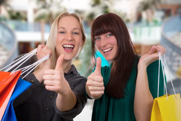 Smiling young women having fun while shopping in a shopping mall — Stock Photo, Image