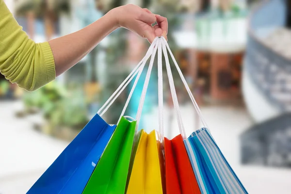 Mujer joven sosteniendo bolsas de compras en un centro comercial — Foto de Stock