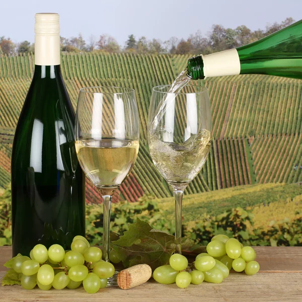 Vinho branco que despeja de garrafa em copo de vinho em vinhas — Fotografia de Stock