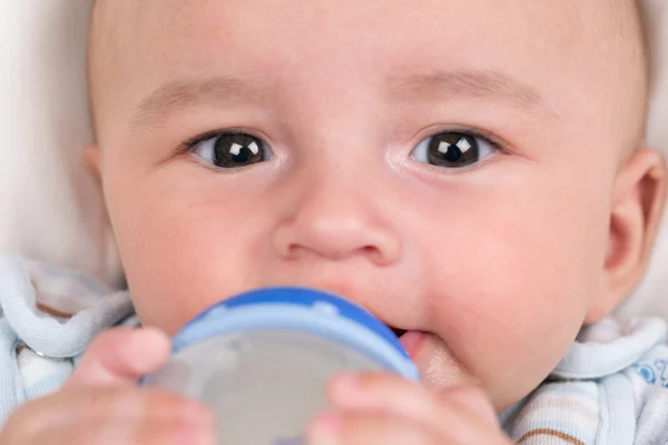 Ребенок пьет молоко и держит бутылку. — стоковое фото