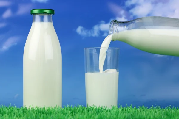 Milk pouring from a bottle into a glass — Stock Photo, Image