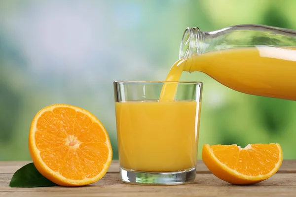 Jus d'orange gieten in een glas in de zomer — Stockfoto