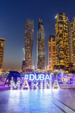 Dubai Marina logosu ve Harbour gökyüzü mimarisi lüks seyahat portresi biçimi gece vakti Birleşik Arap Emirlikleri 'nde modern