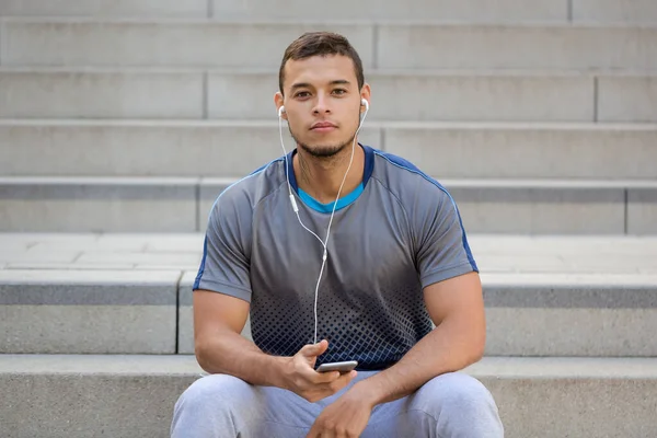 音楽を聴く若いラテン語の男はスマートフォンのスマートフォンの屋外で聞く — ストック写真