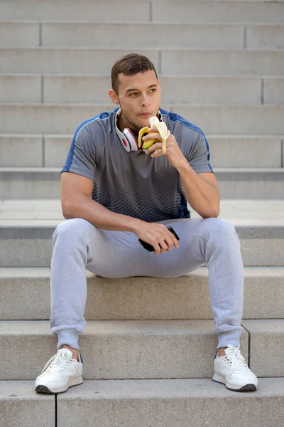 若いラテン人食べるバナナフルーツランナーフィットネス肖像画形式スポーツトレーニング屋外 — ストック写真
